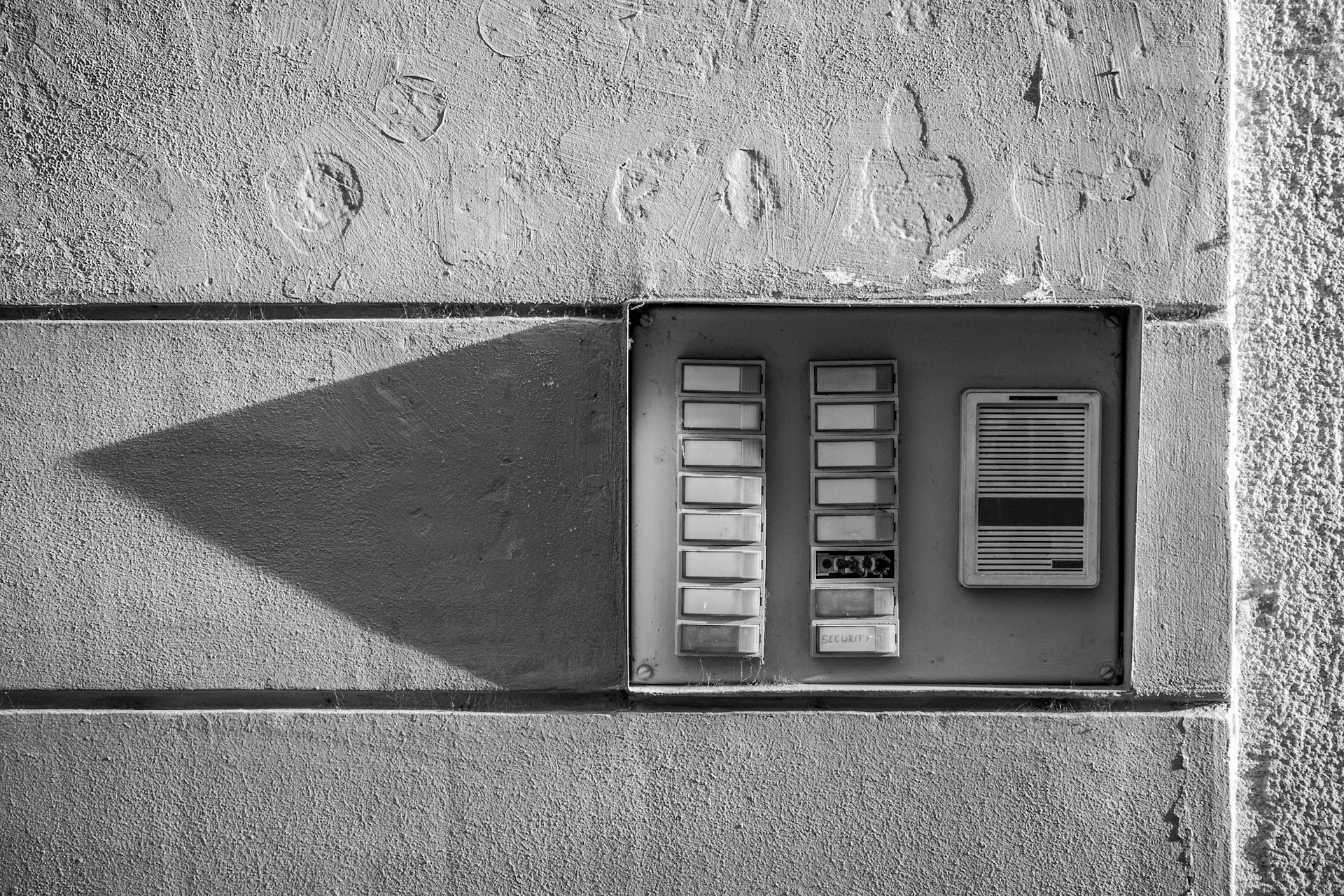 gray scale photo of a wall mounted telephone booth